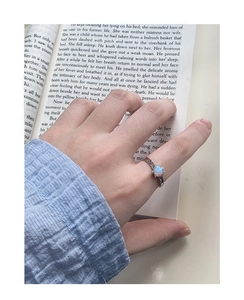 Dettaglio di un anello in argento S925 con opale blu a cuore su un libro aperto