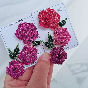 Luxurious rose brooches with colorful crystals and green enamel leaves in various colors