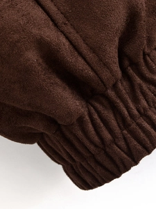 Detailed close-up of dark brown faux suede fabric featuring elastic gathered cuff stitching