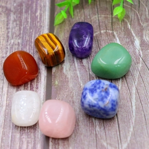 Seven colorful natural polished crystal gemstones arranged on a wood texture background