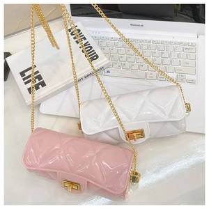 Pink and white quilted jelly bags with golden chain straps on a minimalist desk setup
