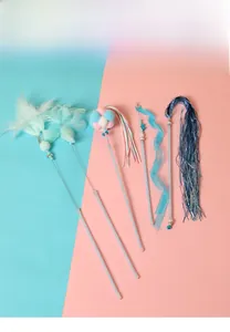 Close-up of assorted cat teaser wands with feathers, bells, and colorful silk ribbons