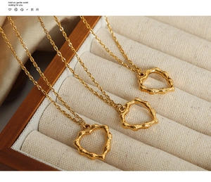 Détail du pendentif cœur doré à texture bambou et sa chaîne torsadée sur présentoir