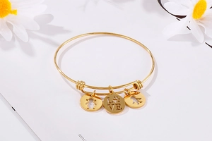 Detail of adjustable gold bracelet with heart, boy, girl pendants and LOVE engraving