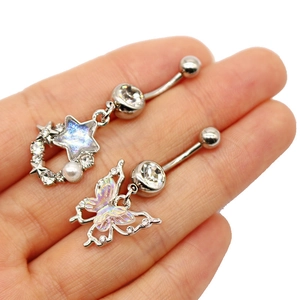 Detailed macro of silver belly rings featuring butterfly and star charms with rhinestones