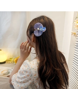 Detail of purple orchid hair clip with pearls worn on model's hair for a sweet look