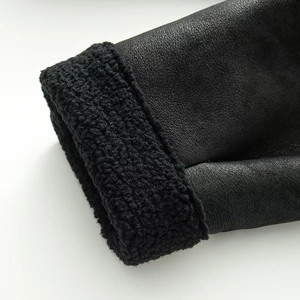 Detail shot of black faux leather and curly faux shearling texture on the jacket cuff