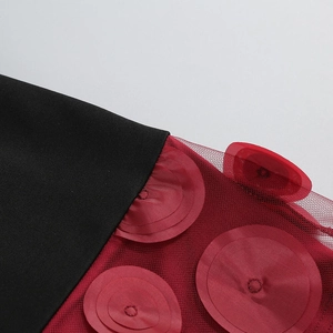 Detail of red mesh fabric with circular floral appliques and black woven texture