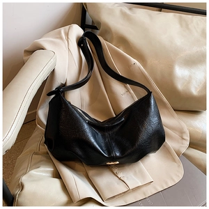 Detail of black pebbled leather crescent bag with knotted shoulder strap and metal zipper