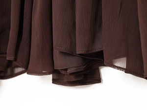 Close-up of deep brown sheer pleated fabric showing lightweight chiffon texture and stitching