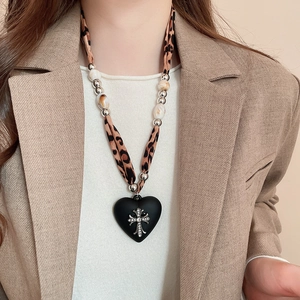 Detail of leopard print cord necklace with heart pendant and sparkling silver cross
