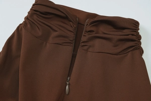 Dettaglio di un abito in maglia a costine marrone con zip posteriore e dettagli arricciati