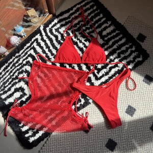 Flat lay of a red three-piece bikini set with a drawstring mesh cover-up skirt detail