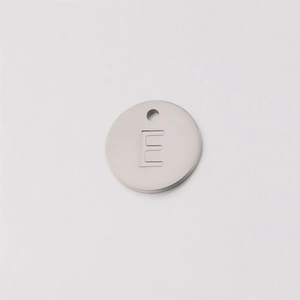 Macro shot of mirror-polished silver stainless steel pendant with engraved letter E