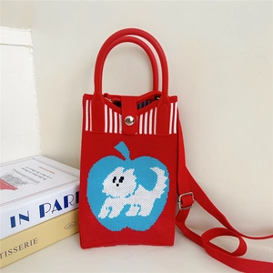 Detail of red knit bag featuring a blue apple motif and white puppy detail inside