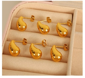 Detailed macro shot of three pairs of glossy 18K gold-plated teardrop stud earrings