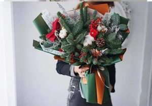 Detail of Christmas bouquet with pine branches, red berries, and cotton flowers with bow