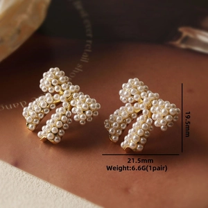 Macro shot of gold bow-shaped earrings with white pearls and size measurements