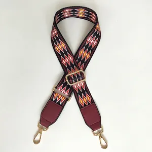 Close-up of red and black diamond pattern wide bag strap with gold lobster clasps