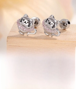 Detail of silver cat stud earring with pink zircon on a rustic wooden base