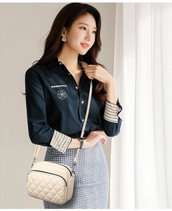 Detail view of a beige quilted crossbody bag with zipper and adjustable strap on a model