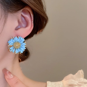 Detailed view of a blue daisy stud earring with textured petals and a golden center