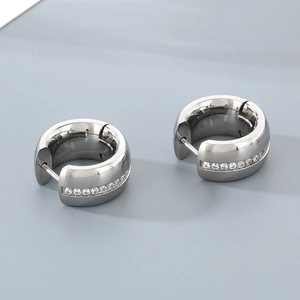 Close-up of polished silver huggie earrings with cubic zirconia inlay design