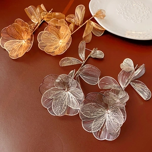 Macro shot of gold and silver hollowed-out wire mesh flower earrings on a textured background