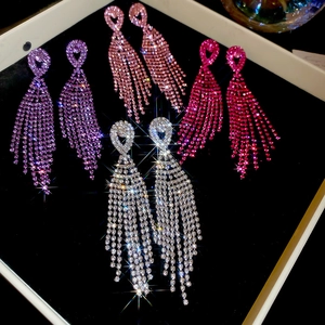 Detailed flat lay of silver needle tassel earrings in purple pink and rose drop rhinestones