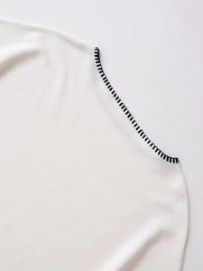 Detailed close-up of high-quality white knit fabric with precise black contrast stitching