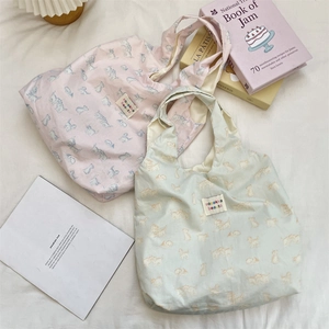 Close-up of pastel canvas tote bags featuring cute cat prints and woven brand labels