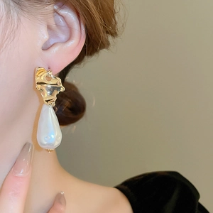 Close-up of vintage irregular golden drop earrings with large baroque pearls on a model