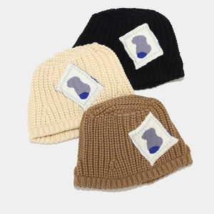 Thick knit bucket hat for women in black, beige and brown with artistic woven patch