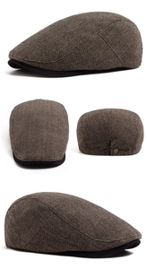 Detail view of herringbone flat cap featuring brown tweed fabric and black brim accents