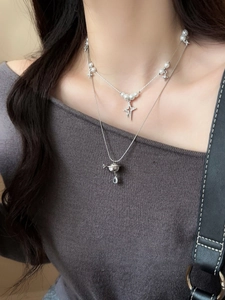 Close-up of double-layered silver necklace with pearl beads, star and planet pendants