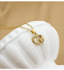 Detail of gold heart pendant with zircon inlay and hollow cat paw design on cross chain