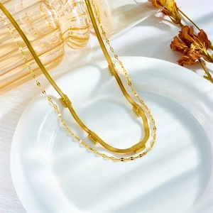 Elegante collana doppia dorata con catena a serpente e pendenti quadrati su vassoio