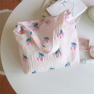 Détail du sac fourre-tout rose matelassé avec broderie cerise et texture gaufrée