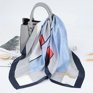 Dettaglio di sciarpa in raso a righe geometriche su una borsa in pelle grigia