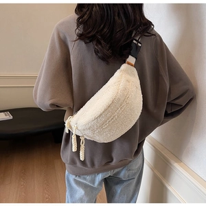 Detailed view of a white fleece crossbody bag with black buckles on a female model