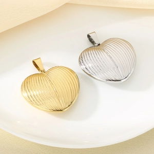 Macro shot of gold and silver heart pendants with vertical stripes on white ceramic plate