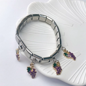 Close-up of Italian style stainless steel bracelet with purple grape charms on shell tray