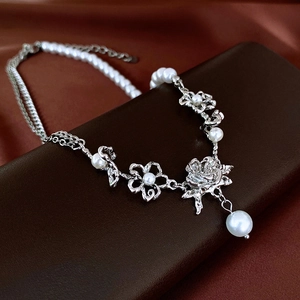 Detail of silver rose flower necklace with faux pearls on premium leather jewelry box