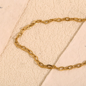 Detail of 18K gold-plated stainless steel chain necklace on textured paper background