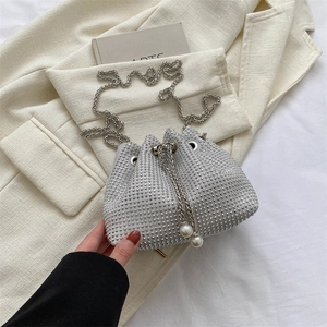 Close-up of sparkling silver rhinestone bucket bag with pearl drawstring and metal chain