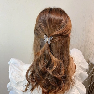 Detailed view of a small transparent butterfly hair claw clip worn on a bun hairstyle
