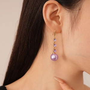 Vintage gold drop earrings with purple crystals and large faux pearls on a model
