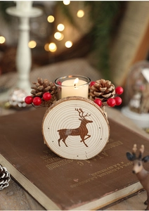 Close-up of wooden reindeer candle holder with pine cones and red berries on vintage book