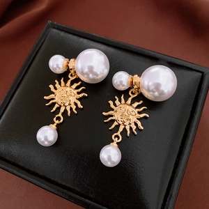 Detail of vintage gold sunburst earrings with tiered pearls on black leather texture