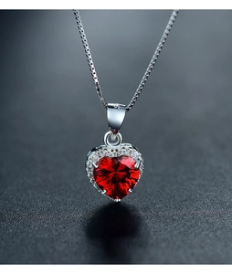 Macro detail of S925 silver heart necklace with red zircon pendant on dark background